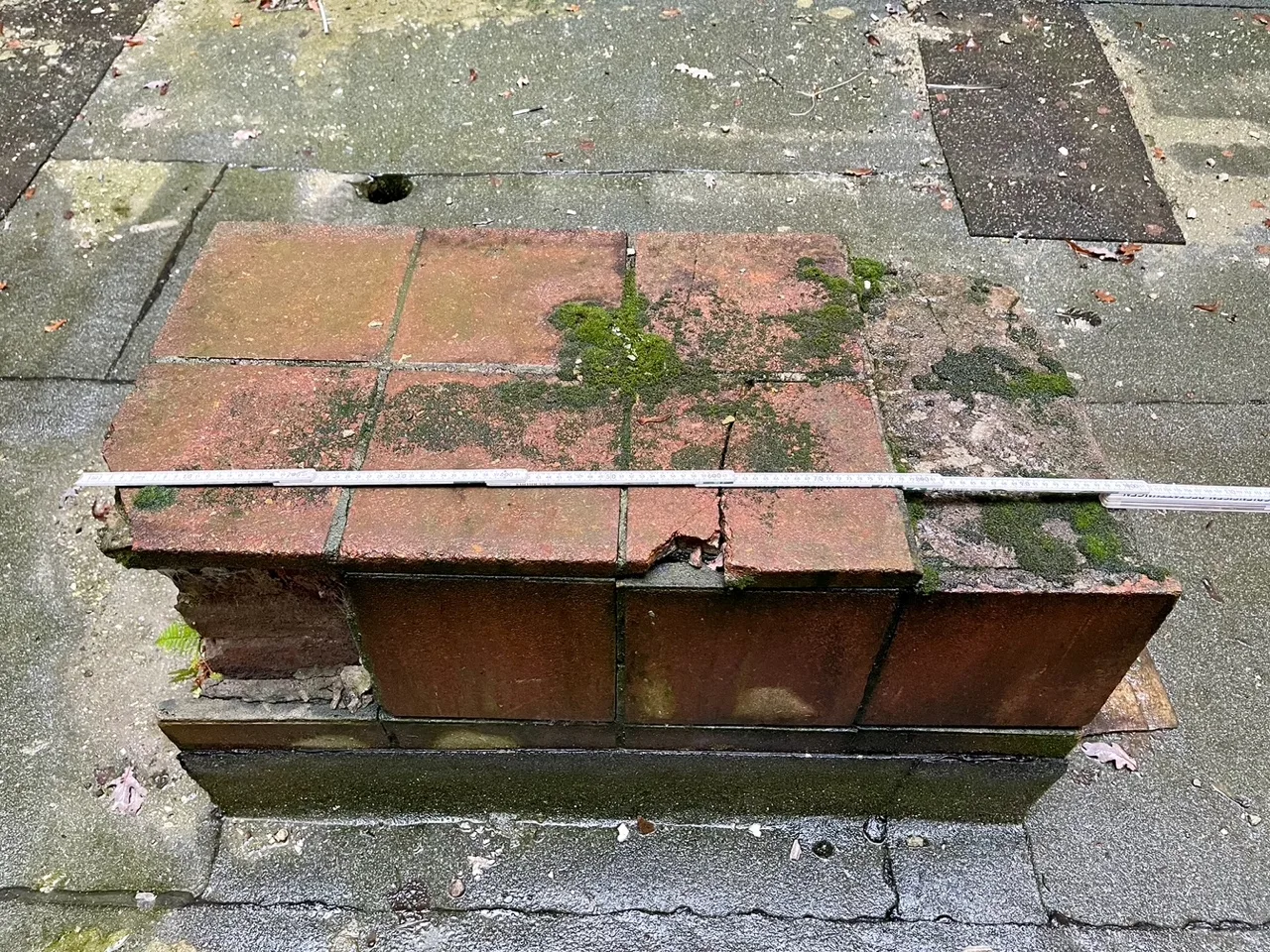 Sandstein-Sockel im Innenhof des Stadtbades Lichtenberg mit angelegtem Zollstock zur Dokumentation der Stellfläche, auf der die Bronzefigur „Ruhendes Mädchen“ stand